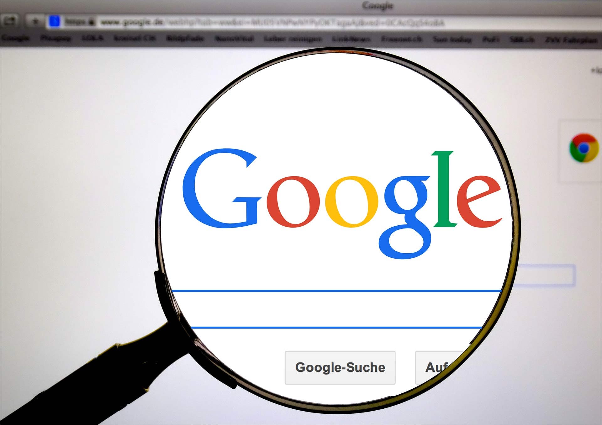 A magnifying glass focuses on the Google logo on a computer screen with an open web browser. The search bar and buttons labeled Google-Suche and Auf gut Glück! are visible.