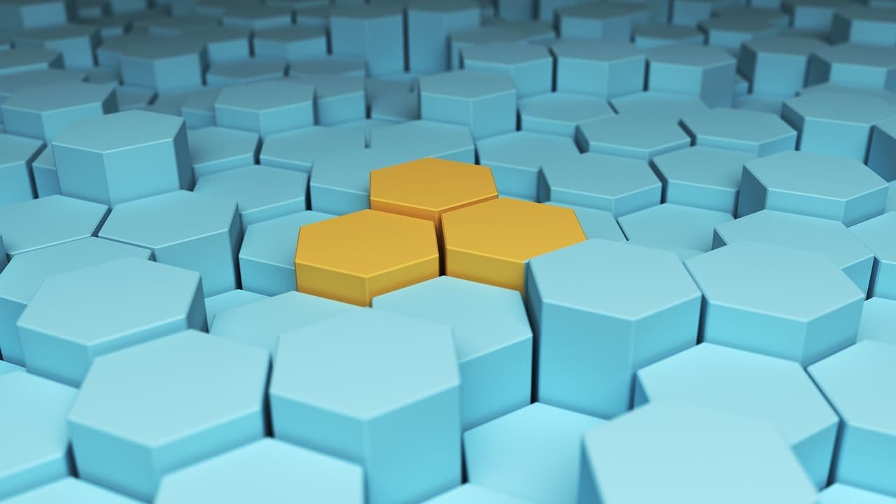 A field of blue hexagonal tiles interlocked in a honeycomb pattern, with three yellow hexagons standing out in the center. The arrangement creates a sense of depth and geometric harmony.