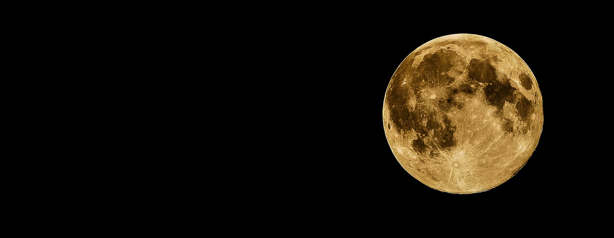 A detailed view of the full moon against a black night sky, with visible lunar surface textures and craters. The moon is positioned toward the right side of the image, leaving a large expanse of dark space on the left.