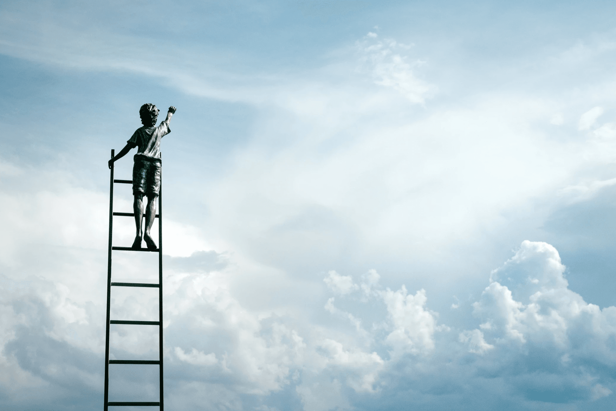 A child stands on the top of a tall ladder reaching up towards the sky, set against a backdrop of expansive clouds and blue sky. The scene conveys a sense of aspiration and wonder.
