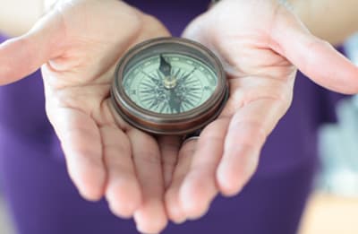 Hands holding an antique compass with a brass rim.