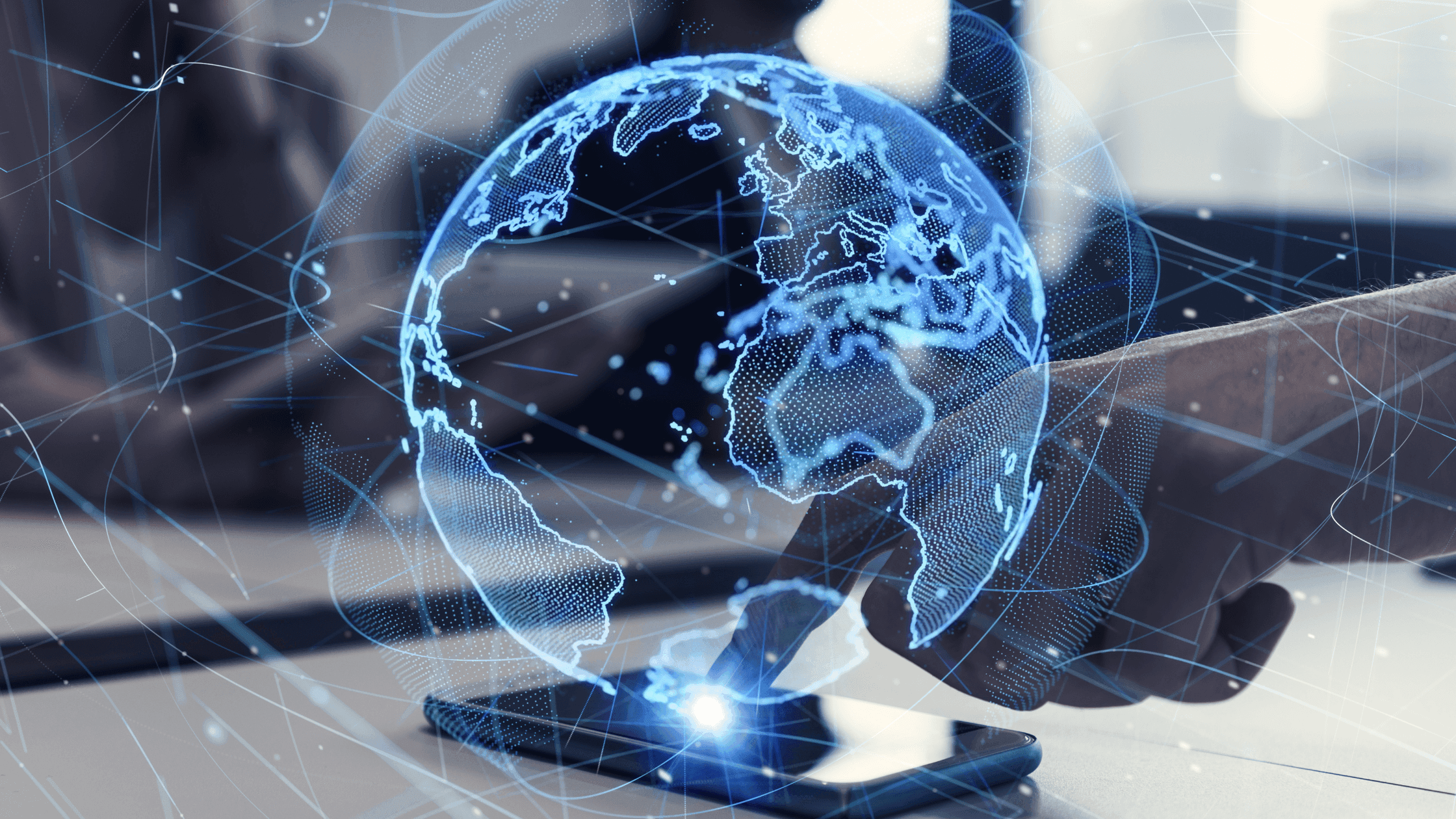 A digital representation of Earth hovers above a smartphone, indicating the concept of global connectivity and technology. The globe is illuminated with blue light, and a hand interacts with the device, set against a blurred background.