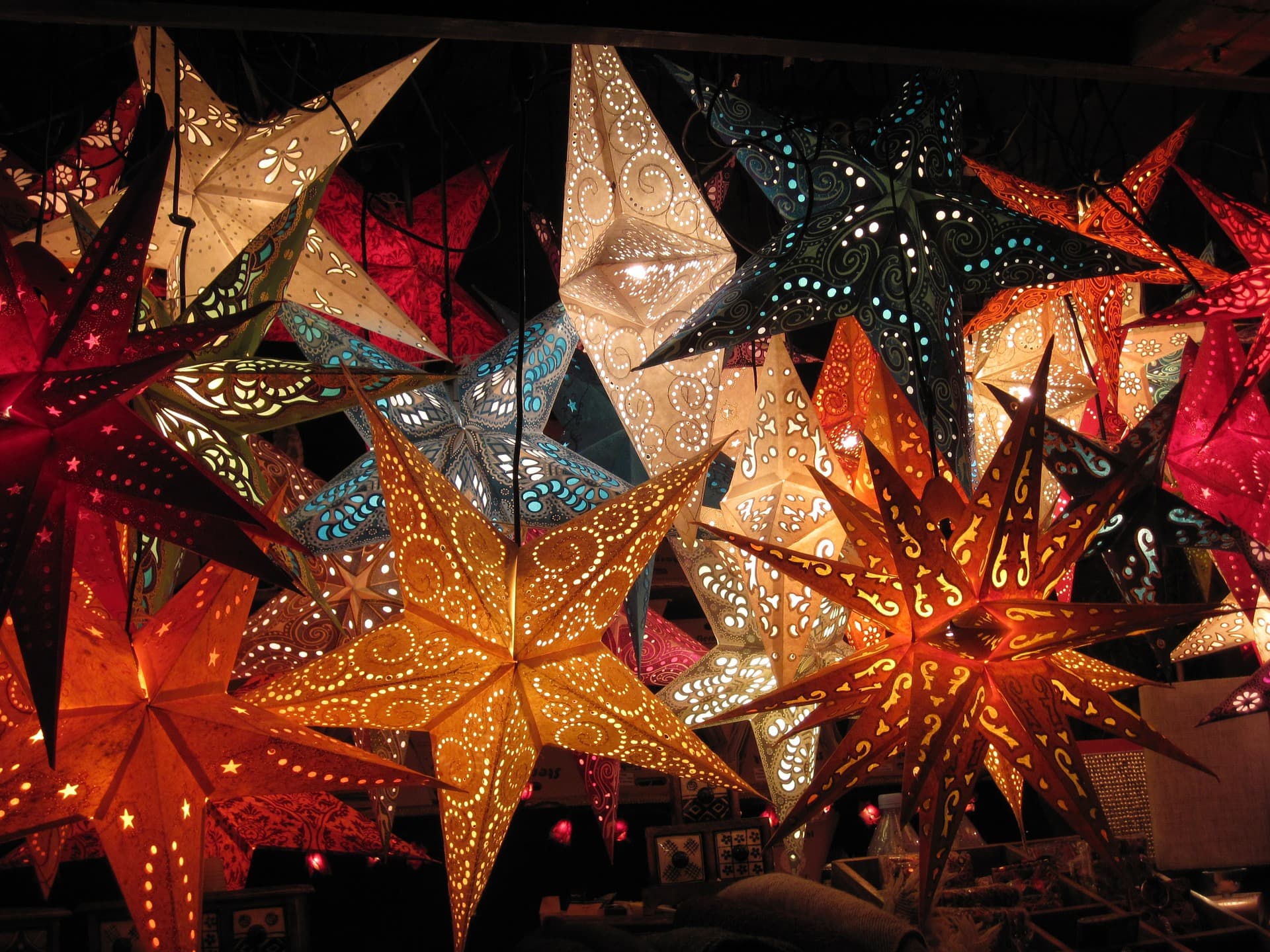 A vibrant display of illuminated star-shaped paper lanterns in various colors and intricate patterns, creating a warm and festive atmosphere.