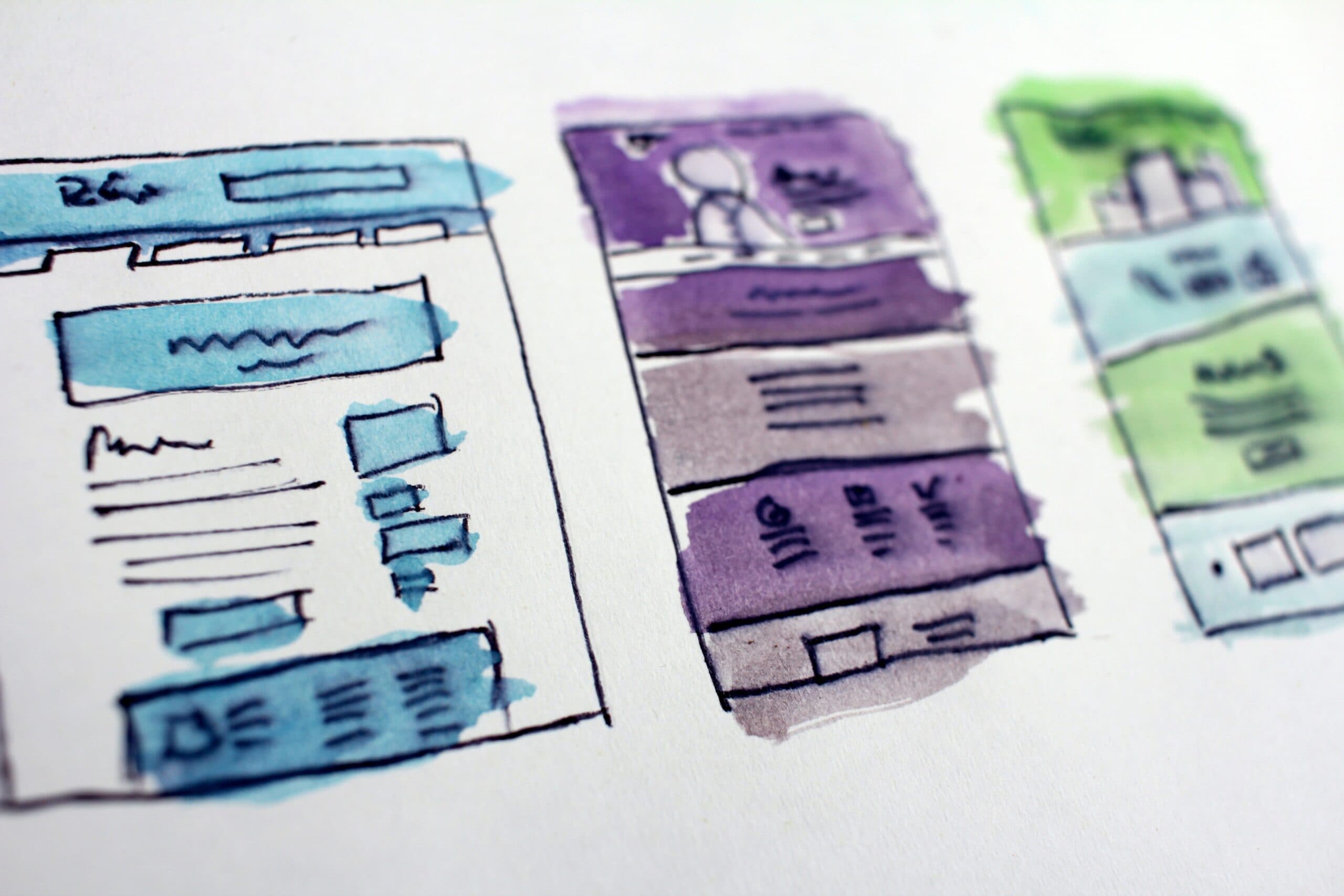 A watercolor sketch of three webpage layouts. The designs feature boxes and lines, representing various website elements like headers and text sections, in shades of blue, purple, and green on a white background.