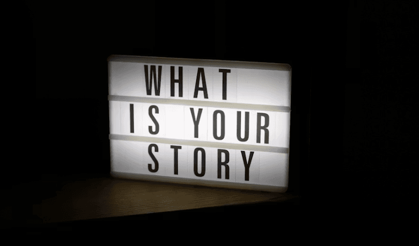 A lightbox in a dark room displays the text WHAT IS YOUR STORY in bold black letters.